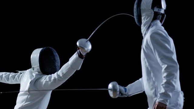 Two Professional Fencers Show Masterful Swordsmanship in their Foil Fight. They Attack, Defend, Leap and Thrust and Lunge. Shot Isolated on Black Background  and in Slow Motion. 