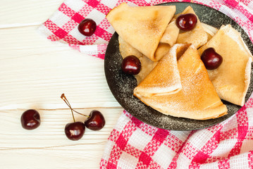 Healthy whole wheat crepes decorated with cherries. Thin pancakes. Top view.