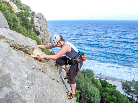 Italien, Sardinien, Kletterin an einer Felswand &uuml;ber dem Meer