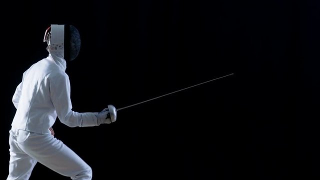 Side View of a Fully Equipped Skilled Fencer Training His Attack and Lunge with a Foil. Shot Isolated on Black Background. Shot on RED EPIC-W 8K Helium Cinema Camera.