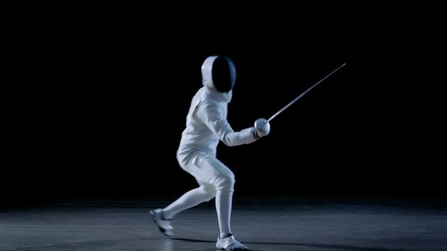Fully Equipped Skilled Fencer Training with a Foil. He Practices Attack, defense,  Leap, Thrust and Lunge. Shot Isolated on Black Background. Shot on RED EPIC-W 8K Helium Cinema Camera.