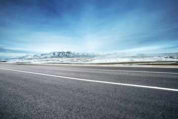 Fototapeta premium empty asphalt road with snow mountains in blue sky