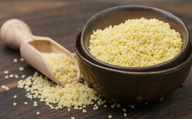 Raw organic couscous in a bowl on the table. Soft focus