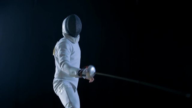 Two Professional Fully Equipped Fencers Expertly Fight with Foils. They Attack, Defend, Leap, Thrust and Lunge. Shot in Slow Motion and on Isolated Black Background. 