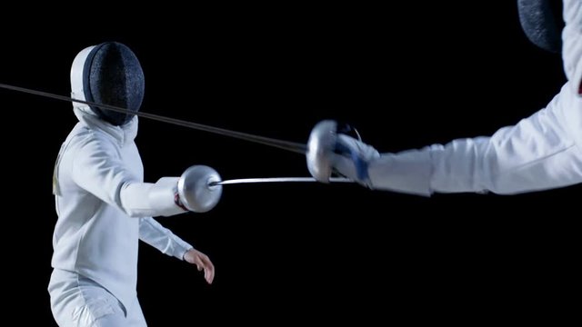 Two Professional Fully Equipped Fencers Expertly Fight with Foils. They Attack, Defend, Leap, Thrust and Lunge. Shot in Slow Motion and on Isolated Black Background. 