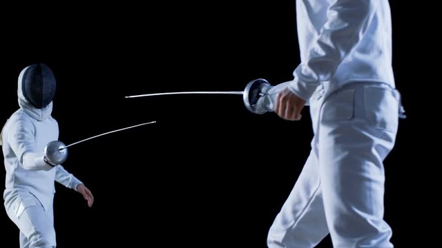 Two Professional Fully Equipped Fencers Expertly Fight with Foils. They Attack, Defend, Leap, Thrust and Lunge. Shot in Slow Motion and on Isolated Black Background. 4K.
