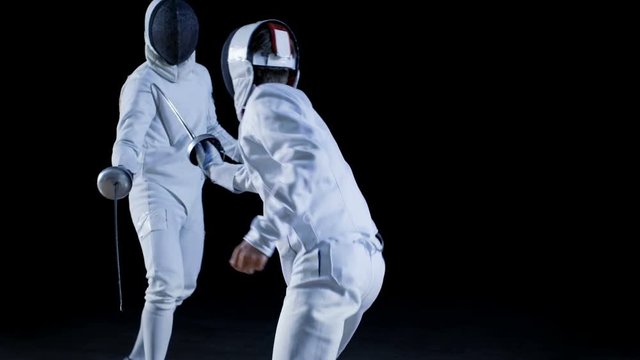 Two Professional Fully Equipped Fencers Expertly Fight with Foils. They Attack, Defend, Leap, Thrust and Lunge. Shot in Slow Motion and on Isolated Black Background. 
