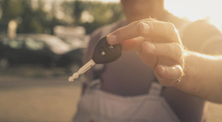 Senior man holding key car. Focus of hand.