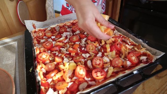 cooking pizza home, the girl puts on the dough, smeared with sauce, pizza ingredients. traditional italian cuisine