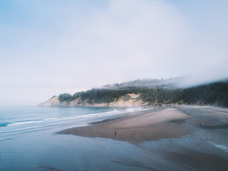 Man alone standing on foggy beach with fog above