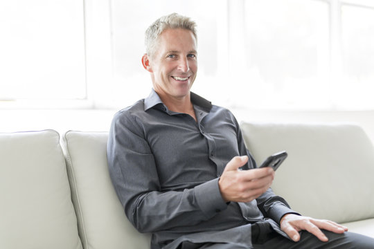 Portrait Of Mature Man Relaxing At Home In Sofa And Cellphone