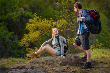 Hikers with backpacks resting on the way to rocks. Travel, vacation, holidays and adventure concept. Forest Mountain landscape background