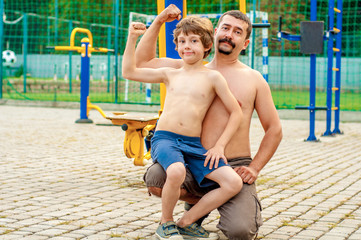 Father and son on the sports ground show strength
