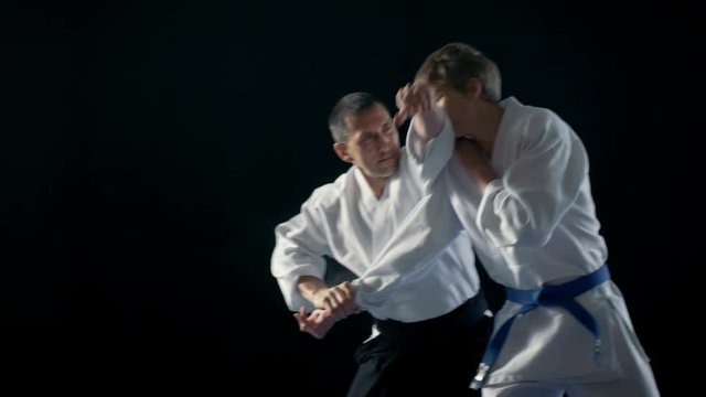 Martial Arts Master Wearing Hakamas Teaches Young Student  Aikido Technique of Throwing over the Shoulder Shot Isolated on Black Background and in Slow Motion. 