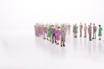 Group of miniature people over white background standing in line.