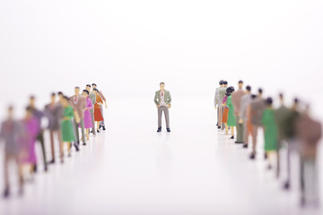Miniature people in two lines across to each other with boss in the middle over white background.
