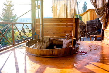 Man and girl relaxing in a wooden jacuzzi - obrazy, fototapety, plakaty