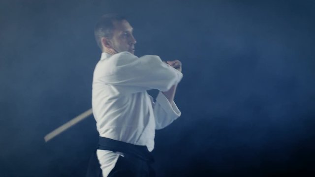 Martial Arts Master Teaches His Young Student How to Fight with Wooden Sword Bokken. Sparring ends in Seconds, Master Wins. Shot is Isolated on the Black Background and in Slow Motion.