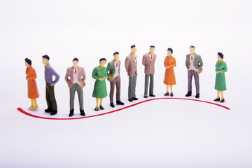 Group of miniature people over white background standing in line or circle.