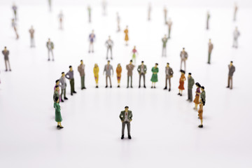 Group of miniature people over white background standing in line or circle.