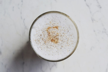 Latte topped with cinnamon and cardamom on marble background