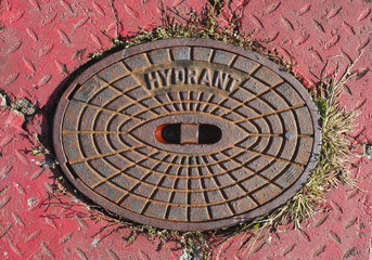 Alter Hydrantdeckel, roter Hintergrund