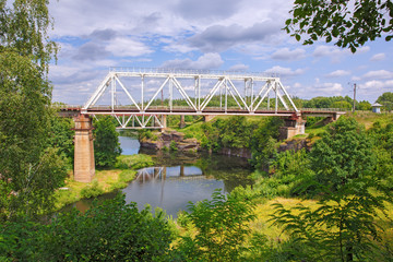 railway bridge through a canyon among green trees against a blue sky with clouds