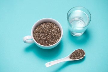 Glass of water with cup of healthy chia seeds and spoon. Text space.