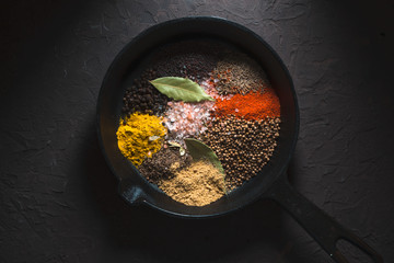 Different spices for Indian masala in the pan on the dark background top view