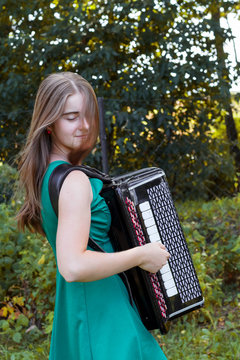 Girl musician plays the the Russian bayan (button accordion) and singing.