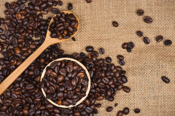 Wooden bowl with roasted coffee beans on rustic background.