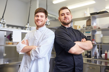 happy smiling chef and cook at restaurant kitchen