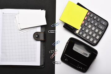 Calculator, note paper, hole punch and paper clips opposite organizer