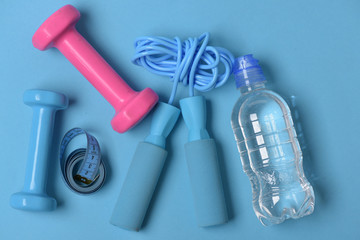 Jump rope and barbells next to bottle and measure tape