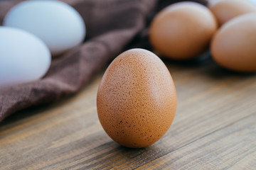 Fresh white and brown eggs in white bowl on a wooden background