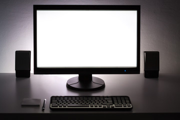 Blank white pc monitor on desktop in organized workplace.