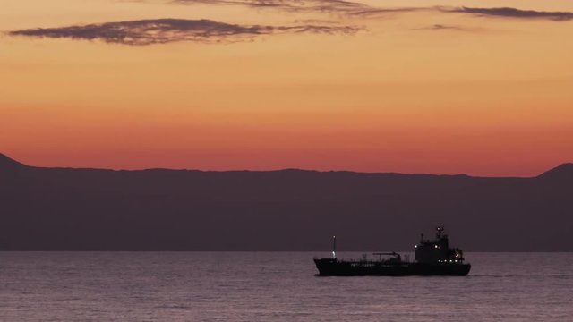 Slow panning shot of an oil chemical tanker passing by, approaching the shore of Crete.