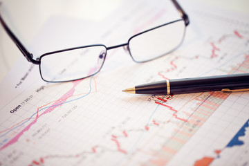Pen and glasses on financial chart business concept analysis of sales plan business report business work station with paperwork