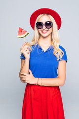 Young woman with summer hat and color clothes bites juicy watermelon isolated on gray background