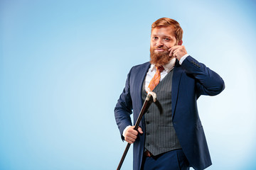 The barded man in a suit holding cane.