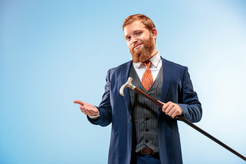 The barded man in a suit holding cane.