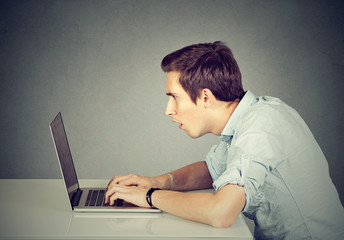 Shocked perplexed man sitting in front of laptop computer looking at screen