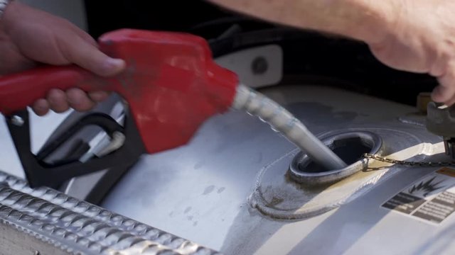 Detail of  truck driver's hands as he finishes filling tank up with diesel fuel. Exterior, real time 4K