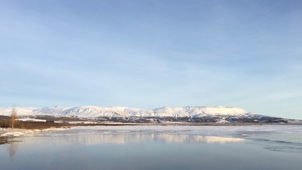 Reflection of snowy mountains on Laugarvatn Lake in Iceland