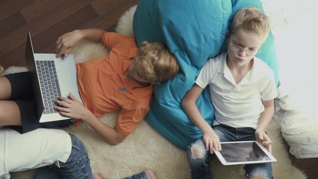 Little boys uses electronic gadgets sitting on floor at home
