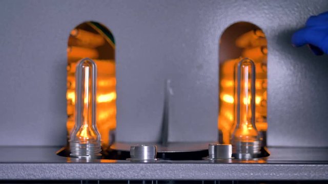 Worker operates a line of plastic preforms in high speed.