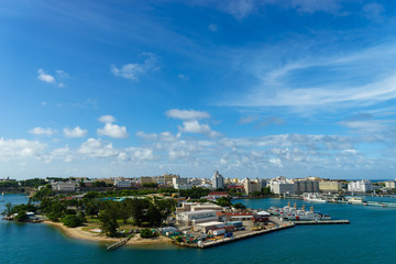 Naklejka na ściany i meble Scenic view of historic colorful Puerto Rico city in distance from the sea with the port in foreground