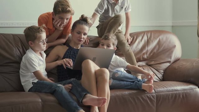 Mother with sons watches movie at laptop at home