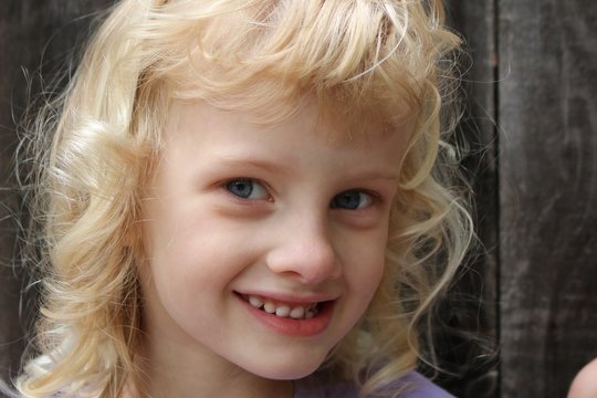 Close up portrait of a young blonde girl with a mischievous smile