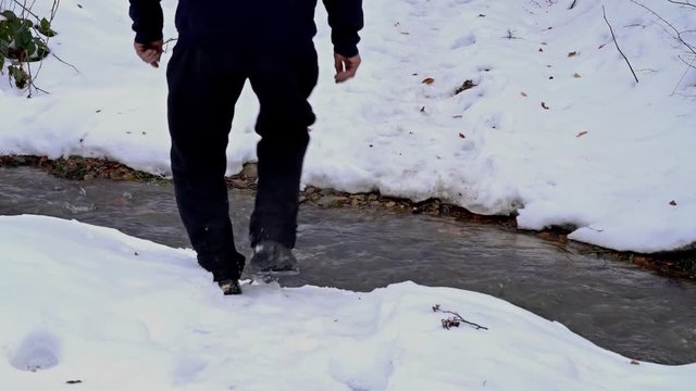 Man crosses the creek in the winter wood - (4K)